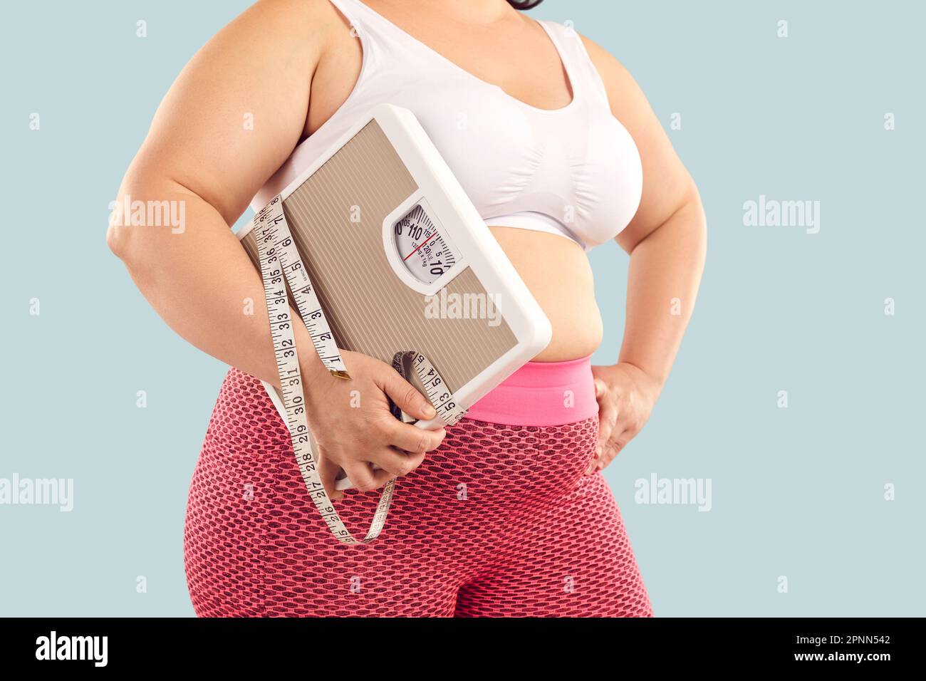 Eine dicke, übergewichtige junge Frau in einem Sport-BH mit Waage und  Maßband Stockfotografie - Alamy