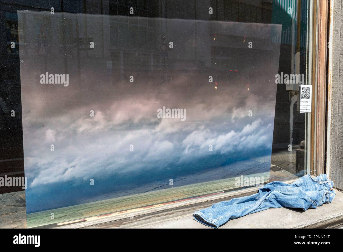 Gemälde, die einen wolkigen Himmel darstellen, der in einem Schaufenster auf dem Fensterbrett sichtbar ist, dessen verlassene Jeans. Brüssel. Stockfoto