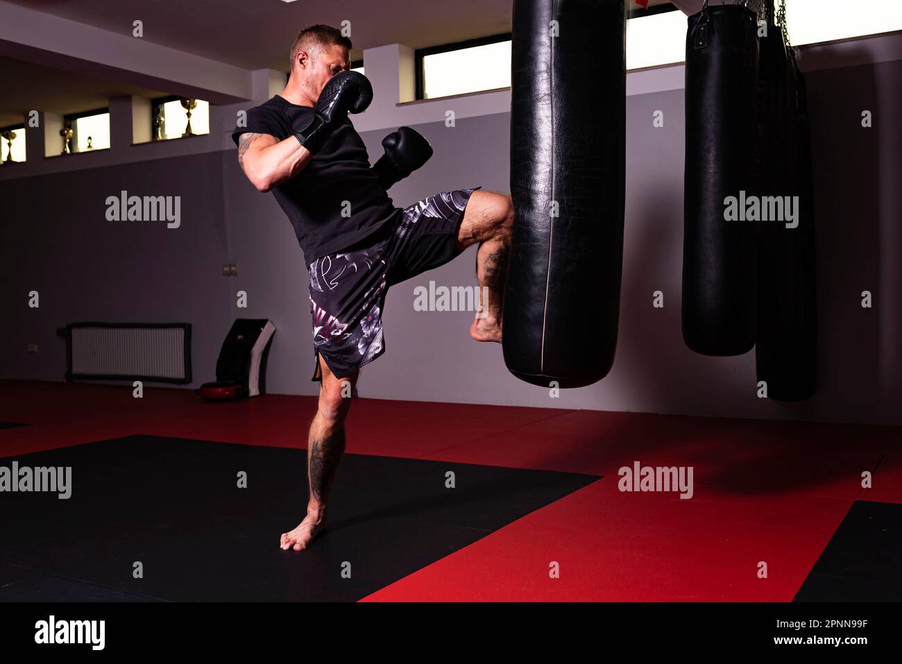 Ein junger Mann nimmt an einem Workout Teil und übt seine Boxfertigkeiten durch einen kräftigen Kick Stockfoto