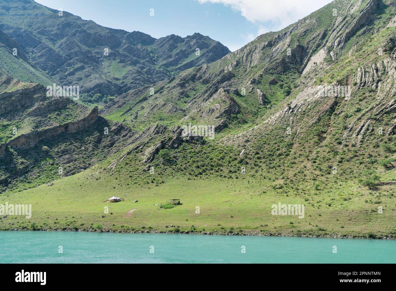 Grüne Landschaft Kirgisistans mit Jurtenzelt neben riesigen Bergen. Kirgisistan ist ein Binnenland in Zentralasien, bekannt für seine rauen, m Stockfoto