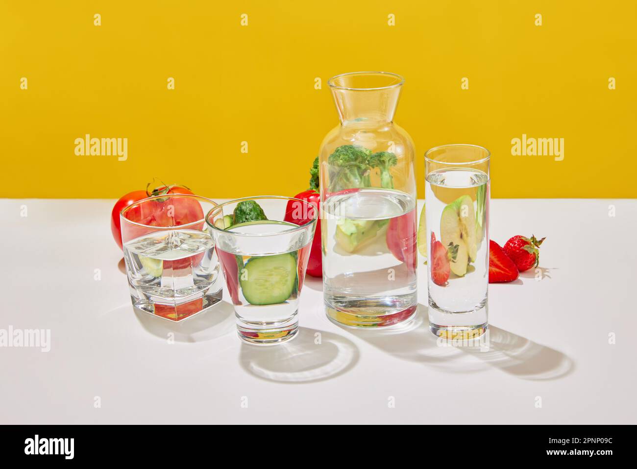 Stille Leben mit saftigem Gemüse und Obst Brokkoli, Tomaten, Pfeffer, Gurke, Erdbeere, apfel auf gelbem Studiohintergrund. Vitamine für Salat Stockfoto