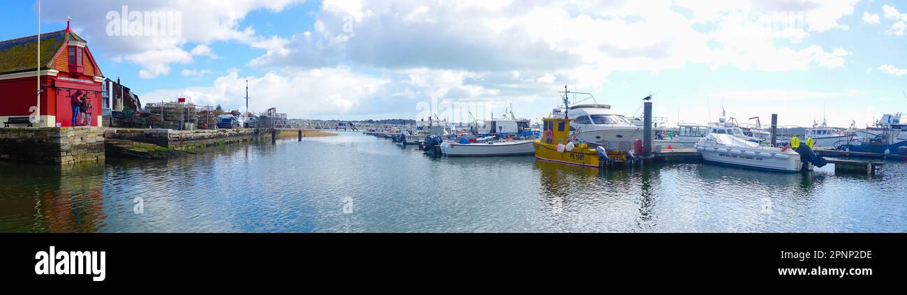 Panoramablick auf Boote, die im Hafen von Poole in Dorset, Großbritannien, vor Anker liegen, mit dem alten roten RNLI-Rettungsboothaus auf der linken Seite. Stockfoto