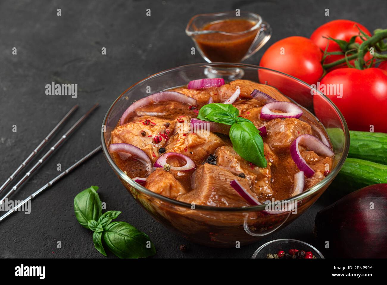 Rohes Schweinefleisch mit Kebab mariniert. Grillfleisch mit Spießen und Gemüse auf schwarzem Hintergrund. Kochen von Grillgerichten Stockfoto