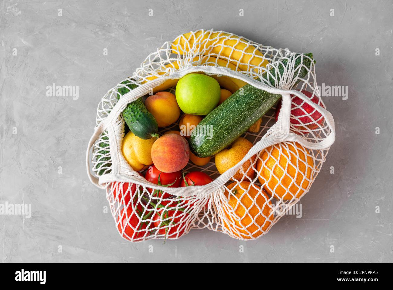 Mesh-Einkaufstasche mit gesunden Bio-Früchten in Gemüse vom Markt. Draufsicht. Vegane oder vegetarische Produkte. Nachhaltiges Lifestyle-Konzept Stockfoto