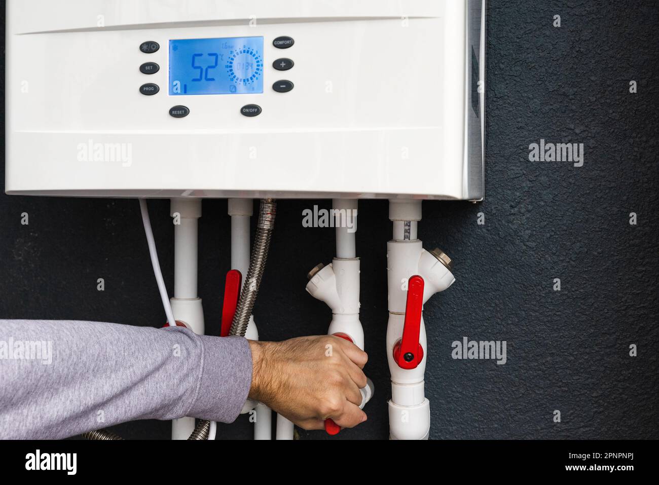 Arbeiter mit Fernbedienung oder Installation eines Gaskessels mit zwei Kreisläufen für die Winterheizungs- und Wasserheizung. Energiesparkonzept und Wärmeschutzkonzept Stockfoto
