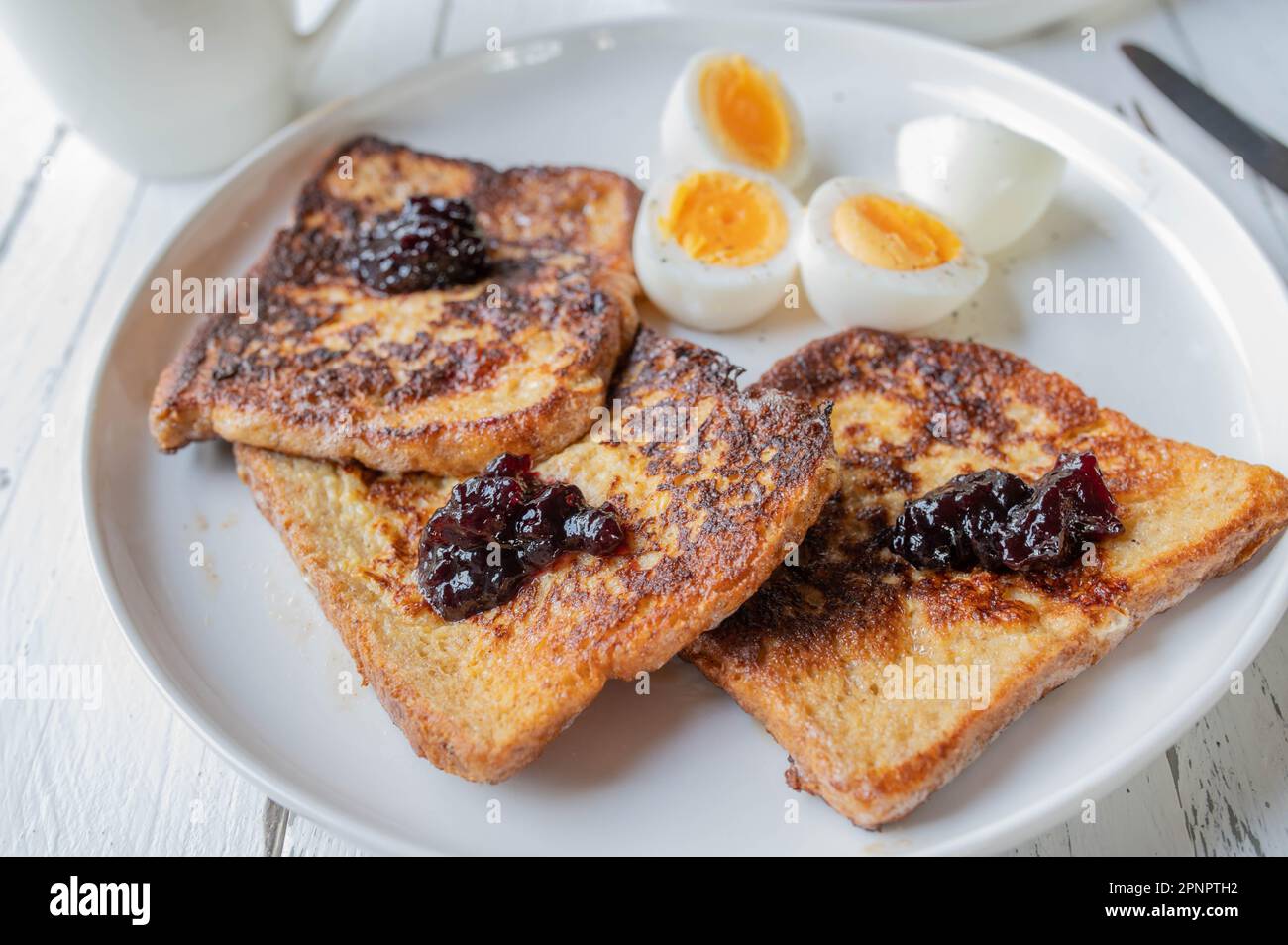 Französischer Toast mit Heidelbeermarmelade und gekochten Eiern auf einem Teller zum Frühstück Stockfoto