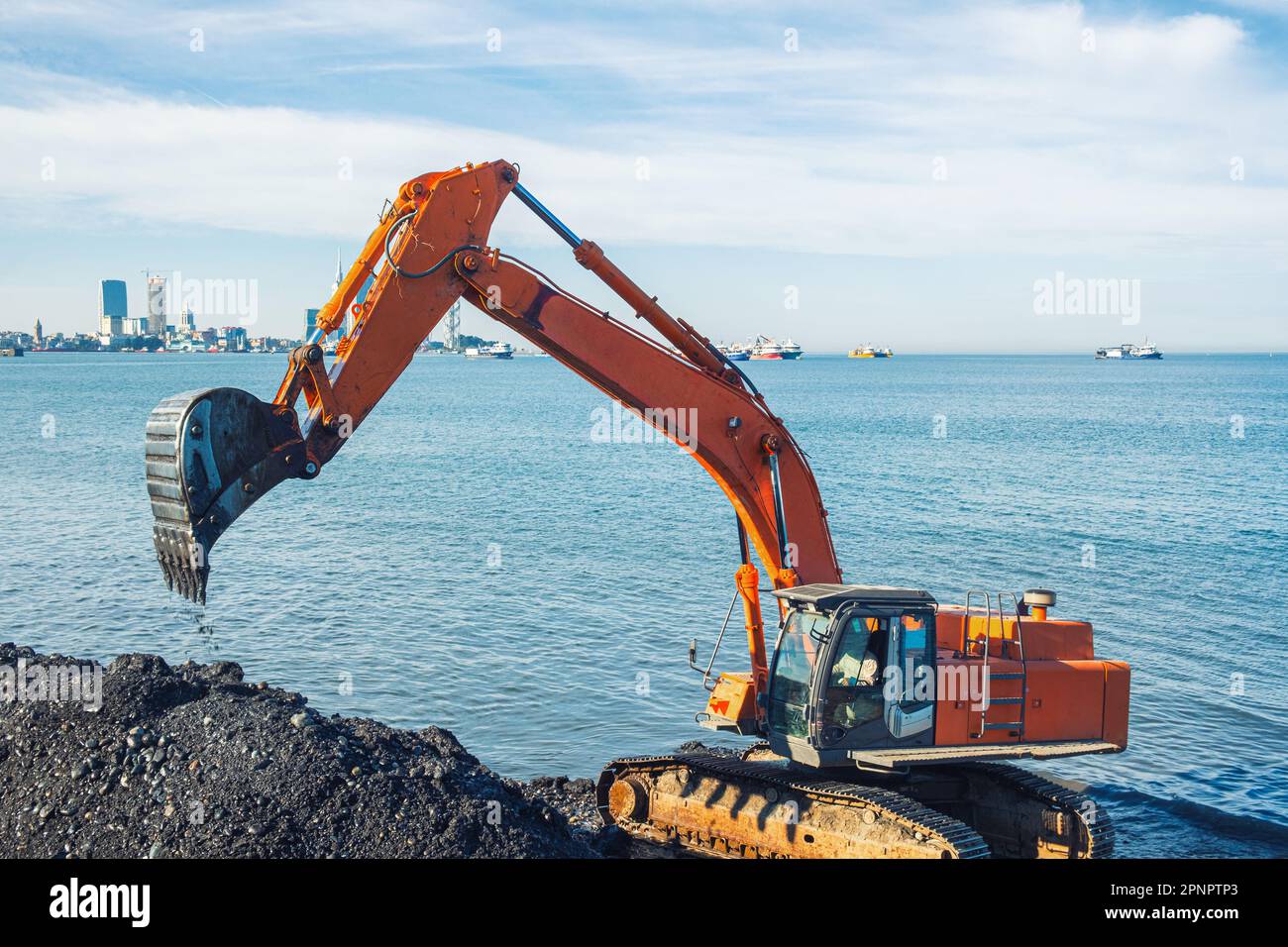 Bagger oder Bagger arbeiten an Erdbewegungsarbeiten in Landschutzarbeiten in Batumi. Orangefarbener Baggerlader gräbt Sand und Kies in Steinbrüchen. Bagger während der Aushubarbeiten Stockfoto
