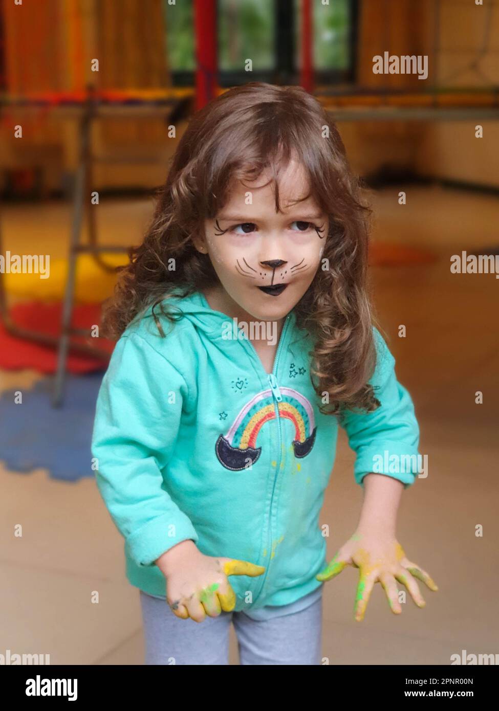 Ein Mädchen mit Hundegesicht und dreckiger Farbe, bedeckte Hände, die in einem Kinderzimmer rummachen Stockfoto