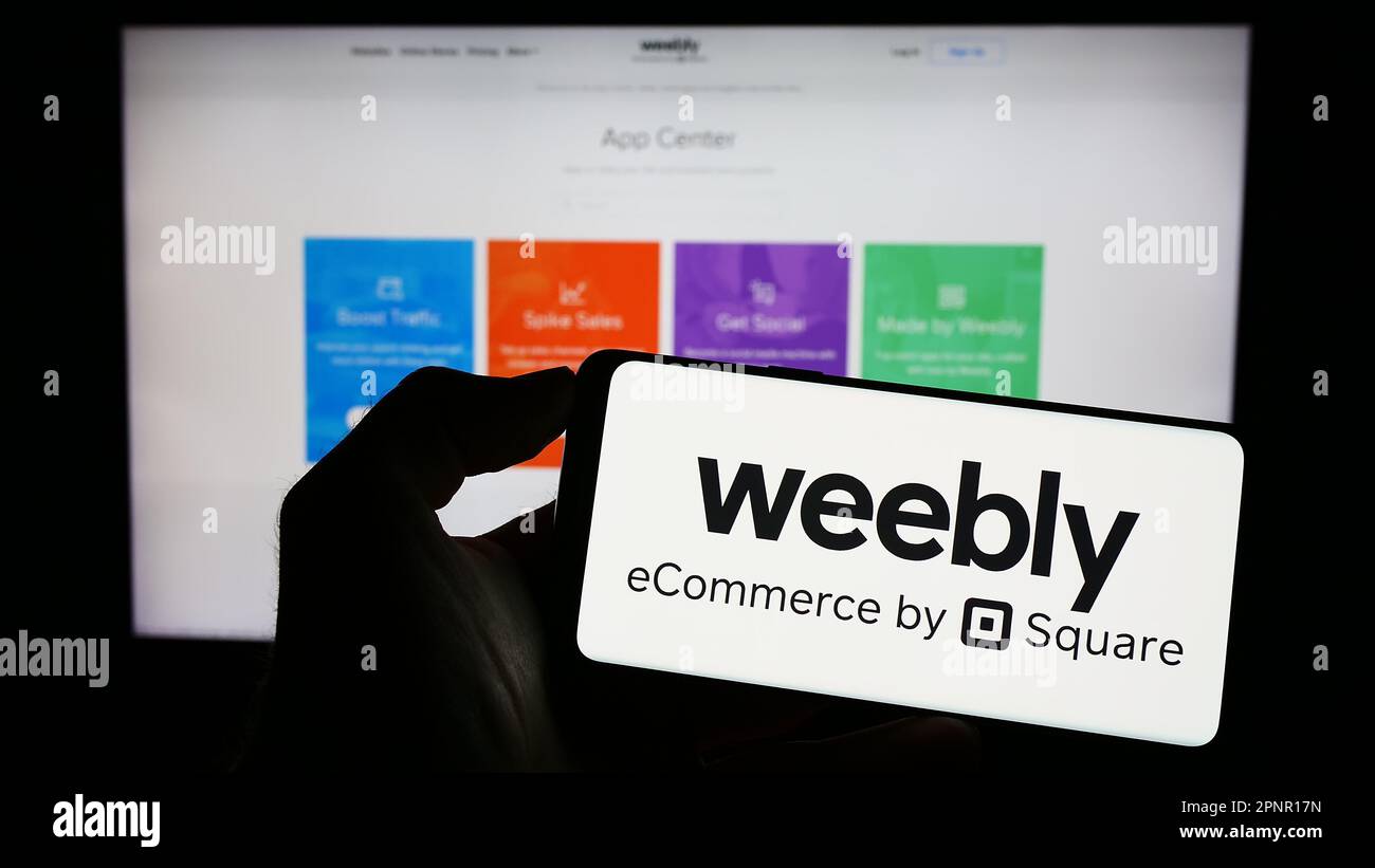Person, die ein Mobiltelefon mit dem Logo des Web-Hosting-Unternehmens Weebly auf dem Bildschirm vor der Unternehmenswebseite hält. Konzentrieren Sie sich auf das Display des Telefons. Stockfoto