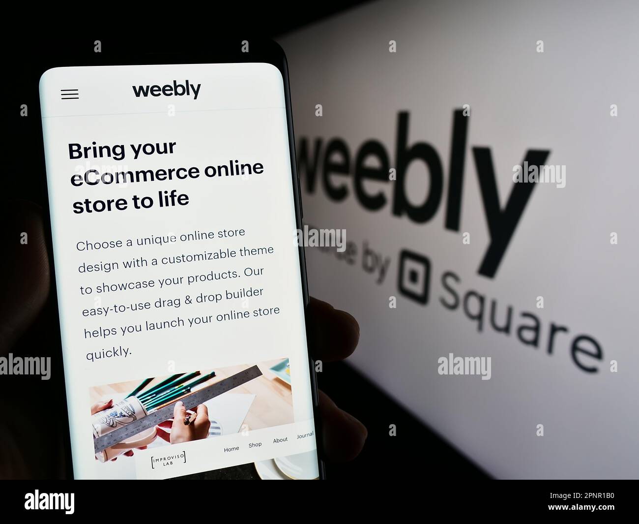 Person, die ein Smartphone mit dem Logo des Web-Hosting-Unternehmens Weebly auf dem Bildschirm vor der Website hält. Konzentrieren Sie sich auf das Display des Telefons. Stockfoto