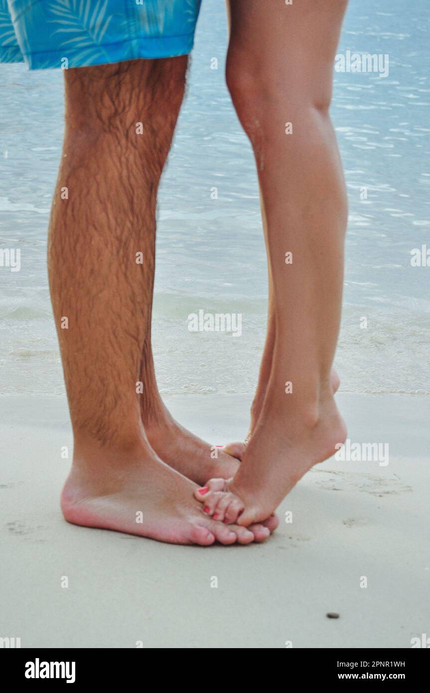 Nahaufnahme einer barfuß Frau, die auf Zehenspitzen auf den Füßen eines Mannes am Strand, Jamaika, steht Stockfoto