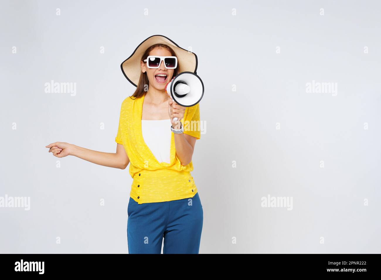 Junge Frau mit Sonnenhut, Sonnenbrille und Megafon isoliert auf weißem Hintergrund. Lifestyle-Sommer- und Ankündigungskonzept. Stockfoto