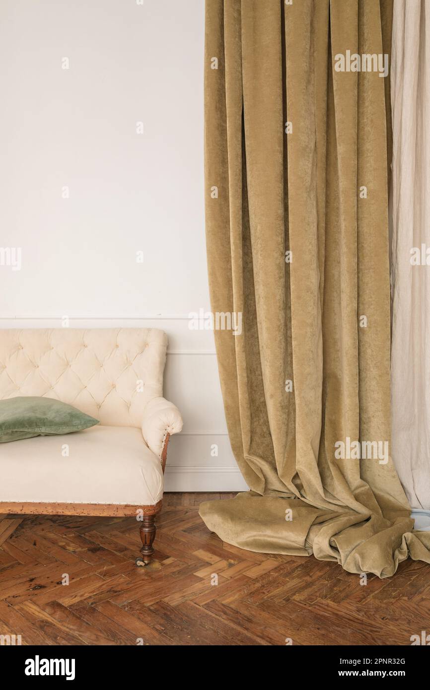 Nahaufnahme eines Sofas im Wohnzimmer neben langen Samtvorhängen Stockfoto