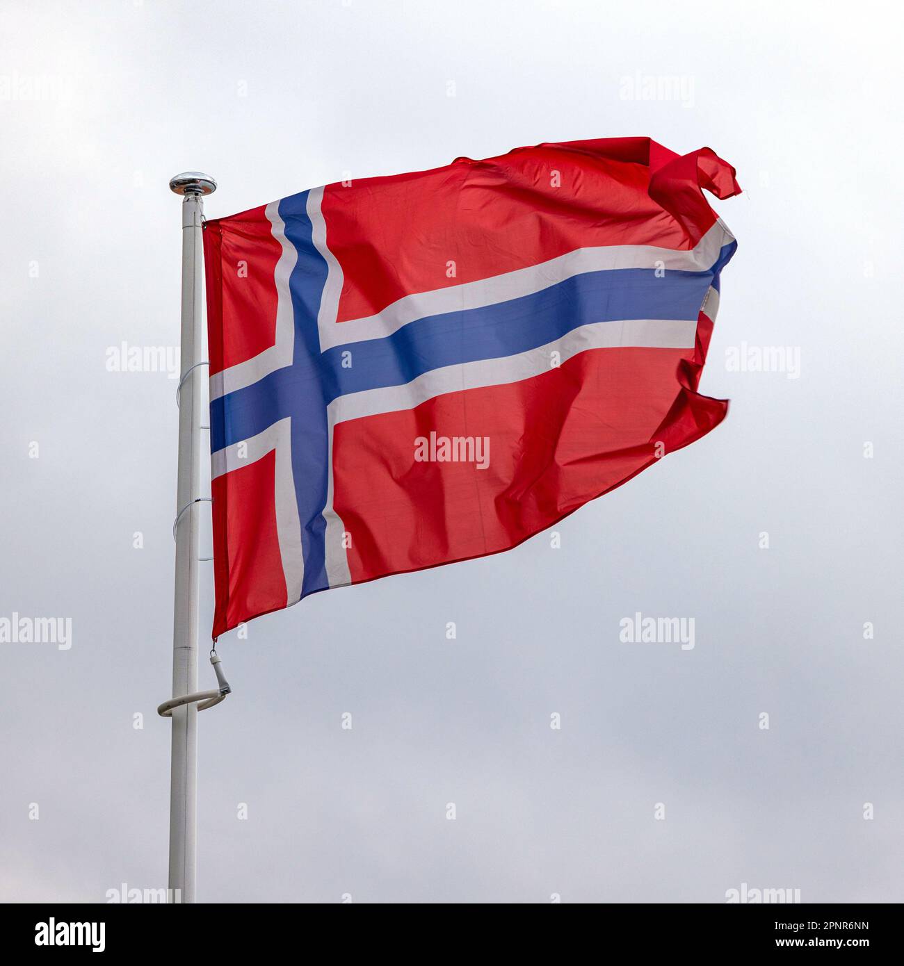 Nationalflagge Norwegens über wolkigem Himmel bei schlechtem Wetter Stockfoto