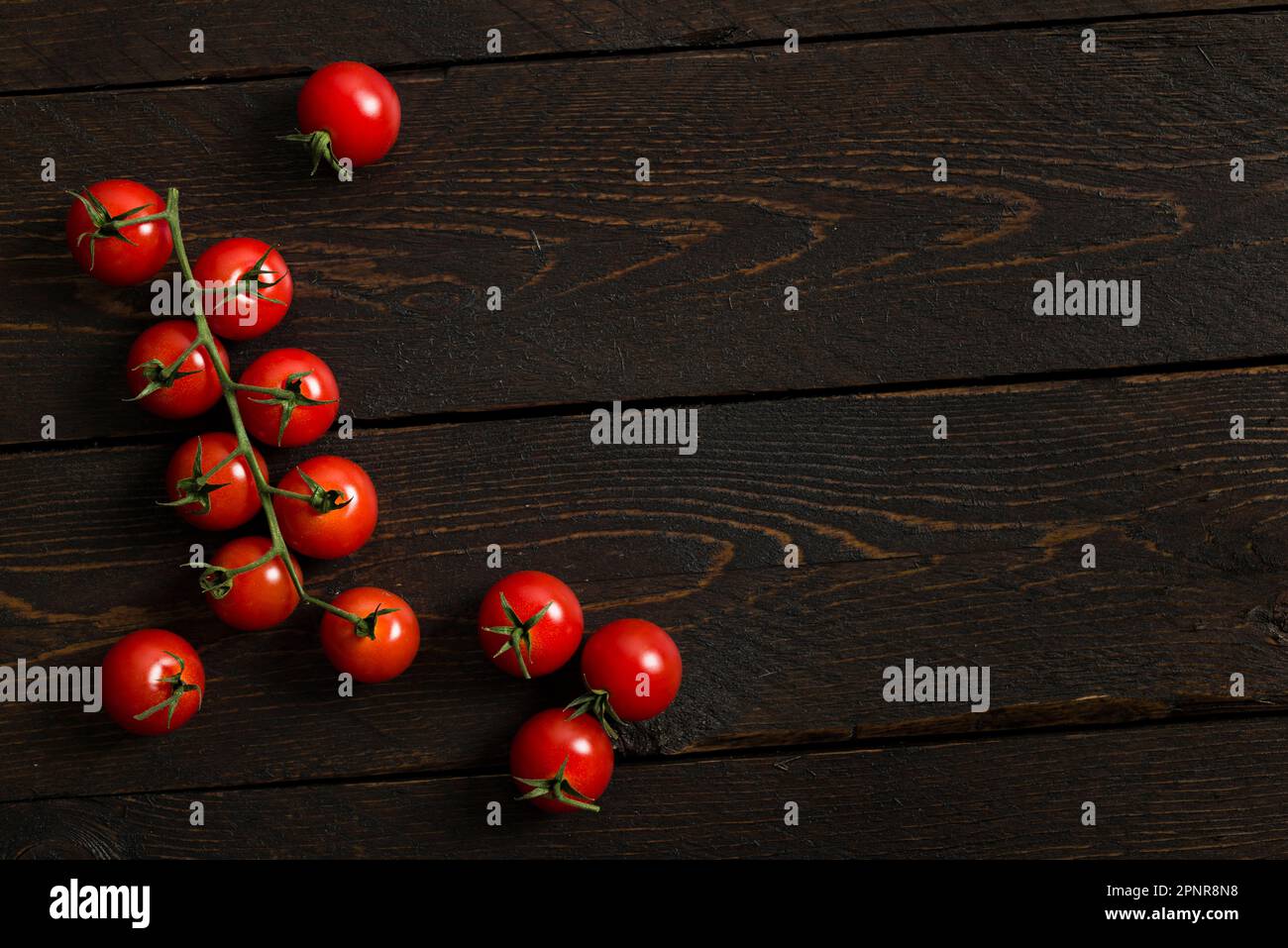 Kleine rote Kirschtomaten auf einem Holztisch. Stockfoto