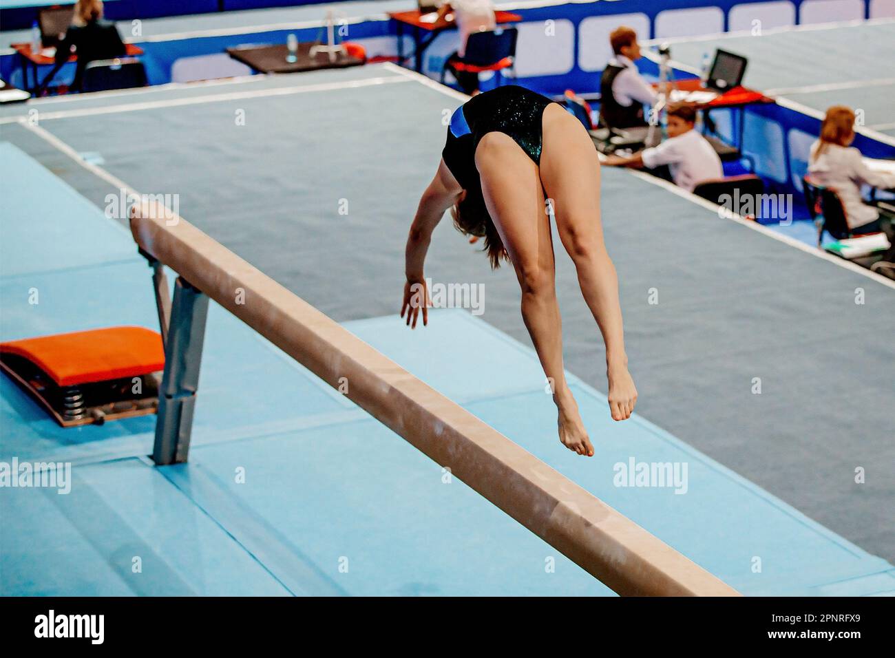 Turnerinnen-Akrobatikelement auf Balancestrahl in künstlerischer Gymnastik, Sommersportspielen Stockfoto