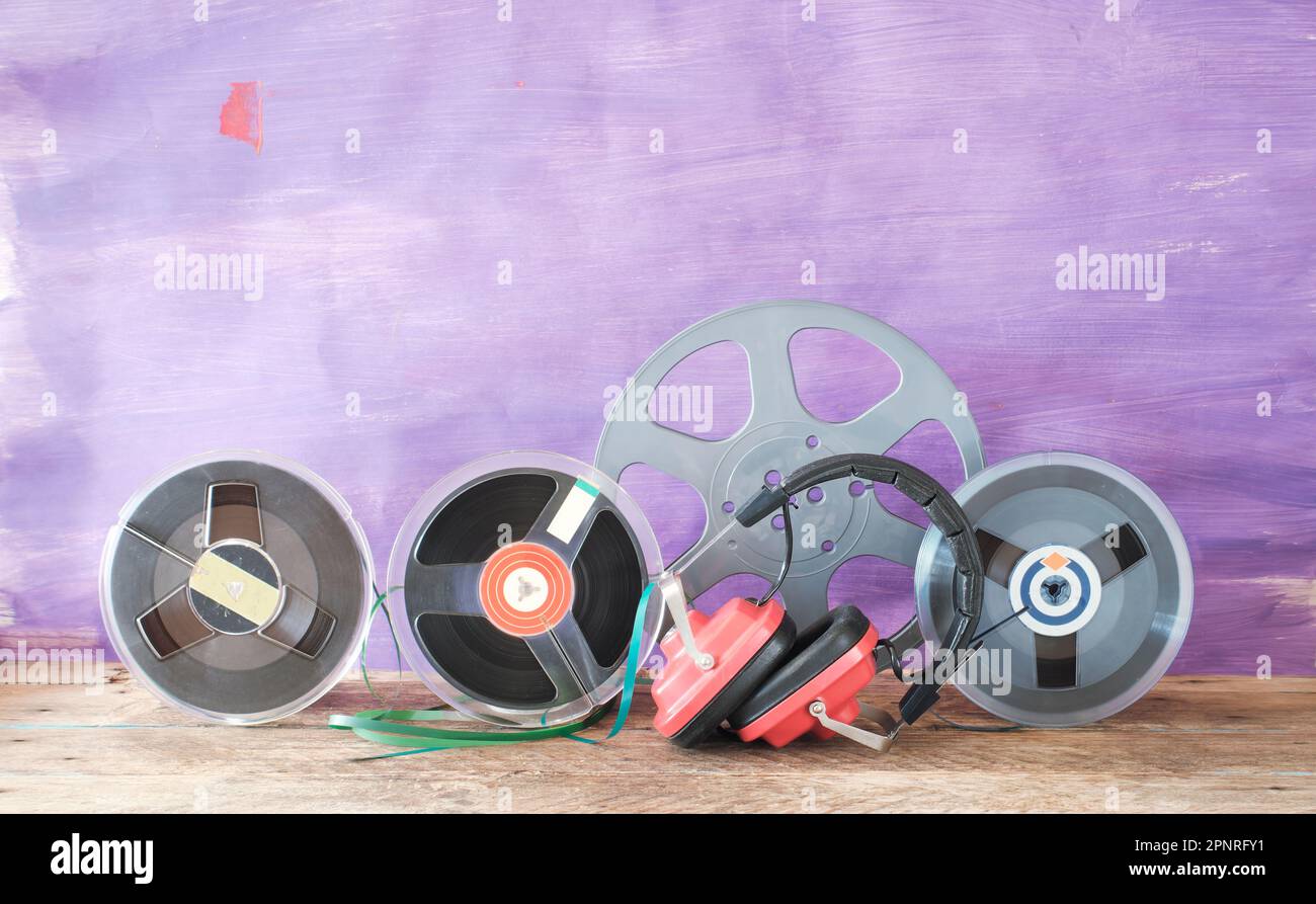 Kopfhörer in Vintage-Rot und magnetische Aufnahmebänder auf Rolle, analoge Farbsimulation, kostenloser Kopierbereich Stockfoto