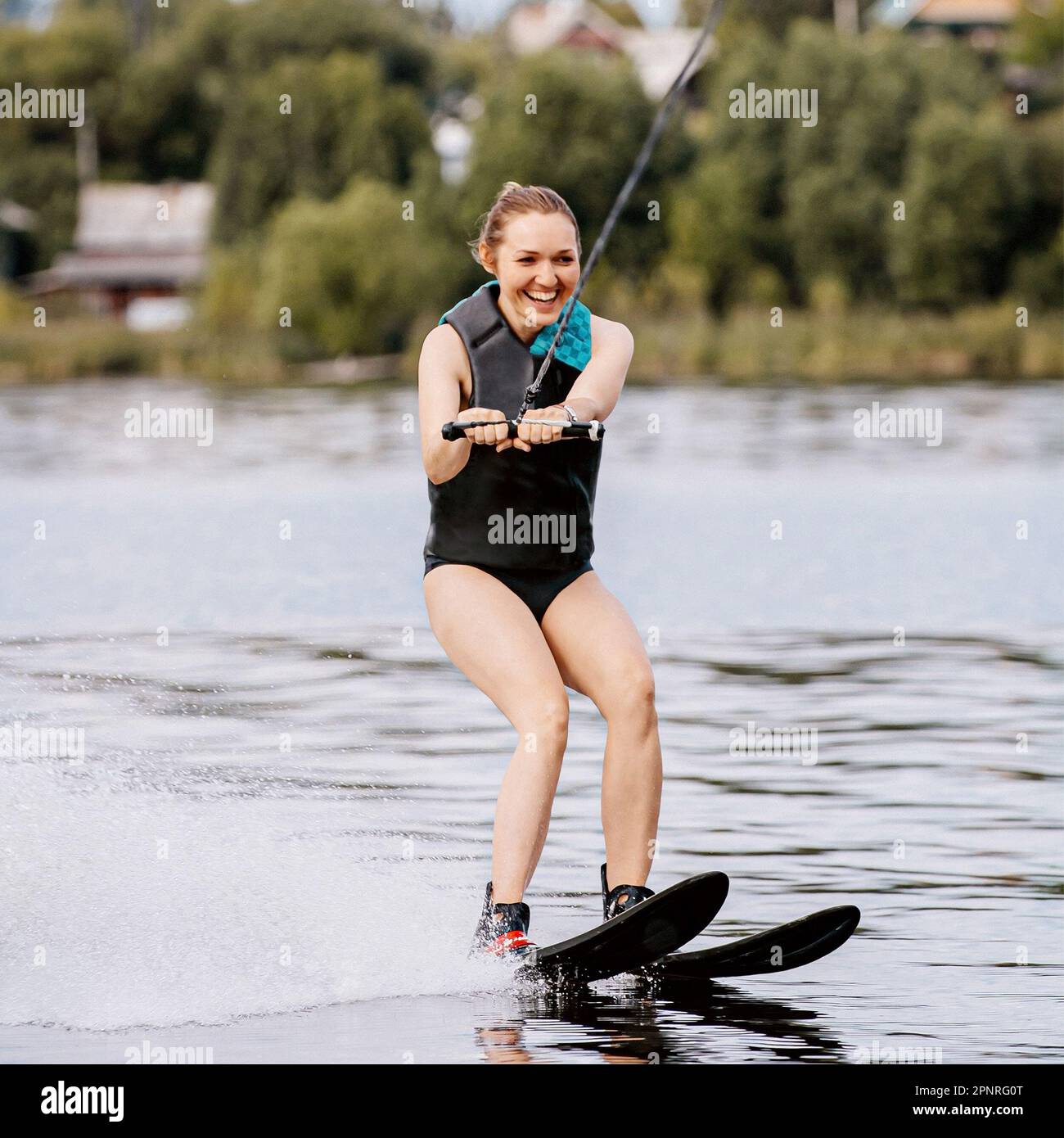 Lächelnde Frau, Wasserski hinter dem Motorboot auf dem Teich, extremer Wassersport, Sommerurlaub Stockfoto