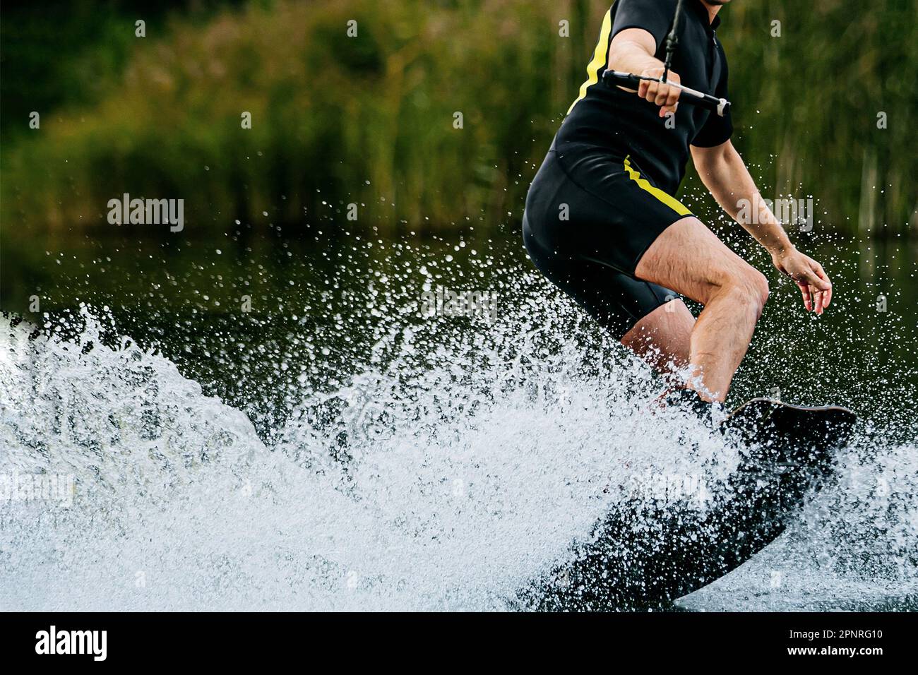 Mann, der hinter einem Motorboot auf dem See wakeboardet, extremer Wassersport, Sommerurlaub Stockfoto