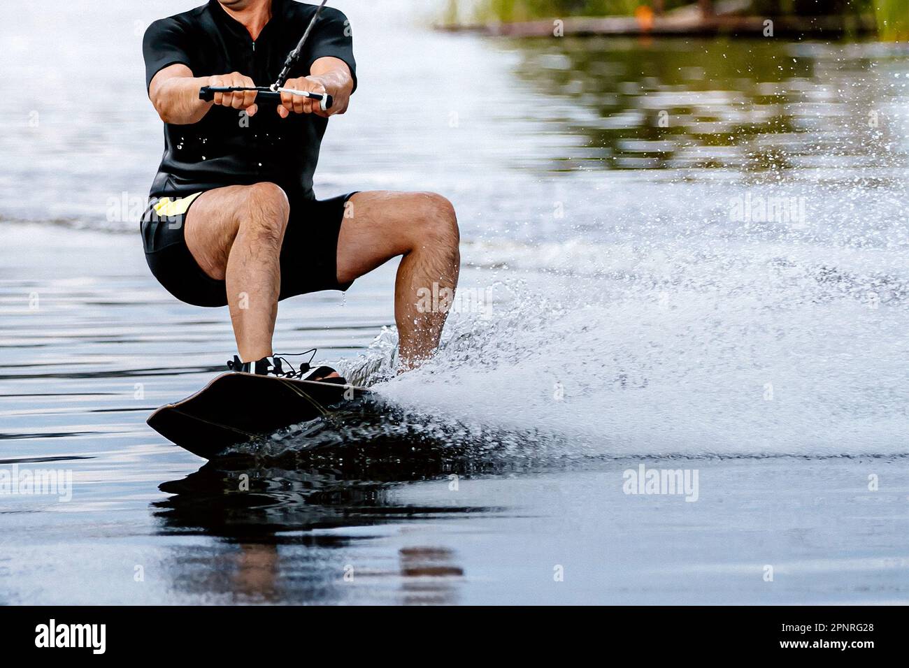 Ein Sportler wacht hinter einem Motorboot auf dem See auf, extreme Wassersportarten im Sommer Stockfoto