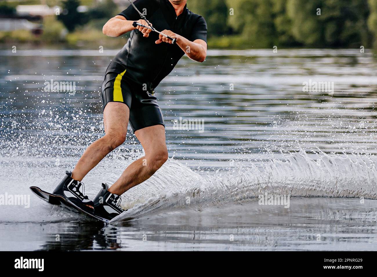 Männlicher Sportler weckte hinter einem Motorboot auf einem Teich, extreme Sommer-Wassersportarten Stockfoto