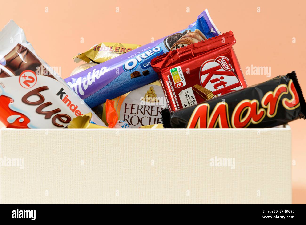 Arahal. Sevilla. Spanien. 18. März 2023. Geschenkbox mit verschiedenen Schokoladen und Pralinen bekannter Marken auf hellorangefarbenem Hintergrund. Stockfoto