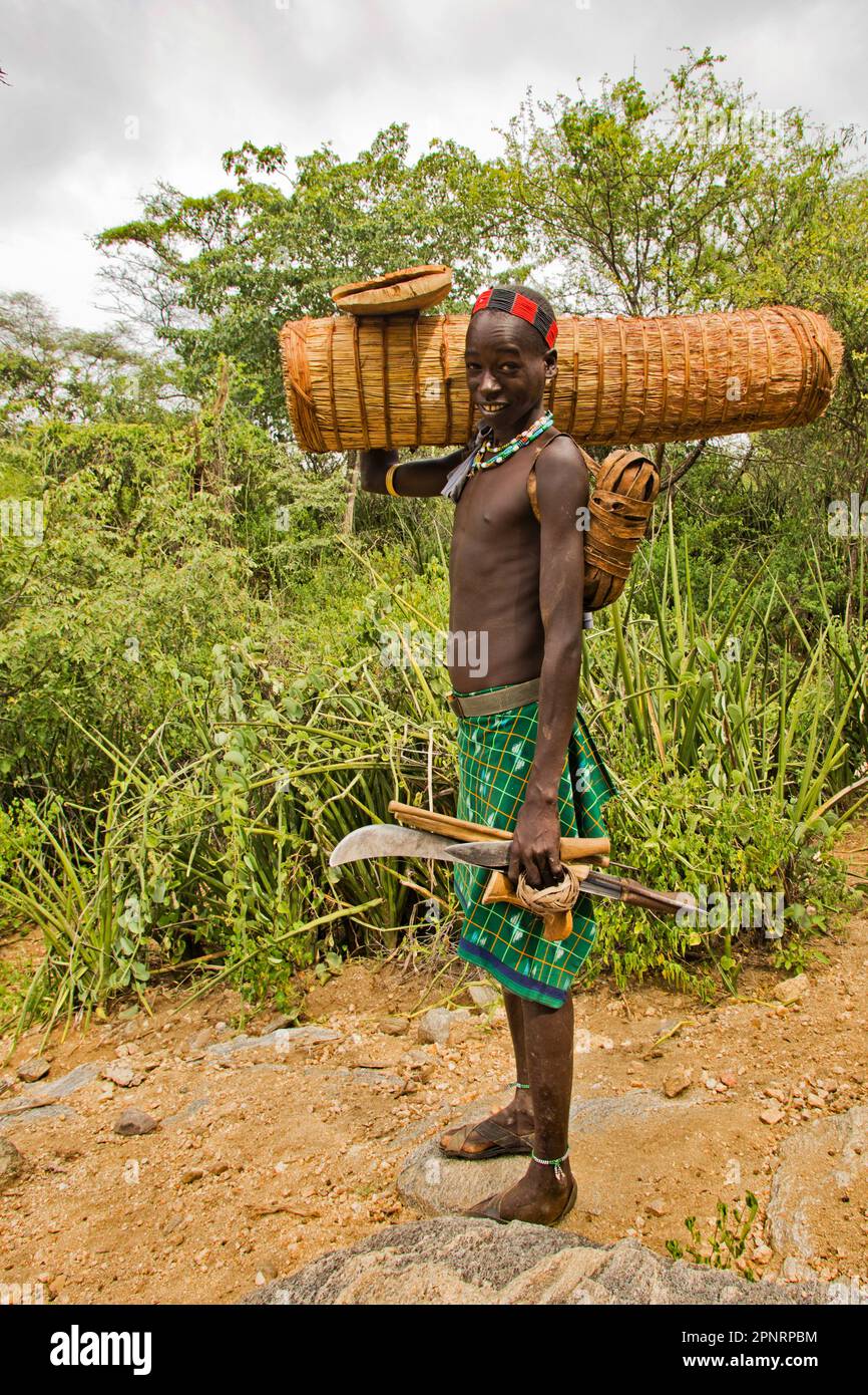 Mann mit einem Bienenstock, der zur Reparatur an einem Baum vorgesehen ist, traditionelle Bienenstöcke des Hamer-Stammes, Äthiopien Stockfoto