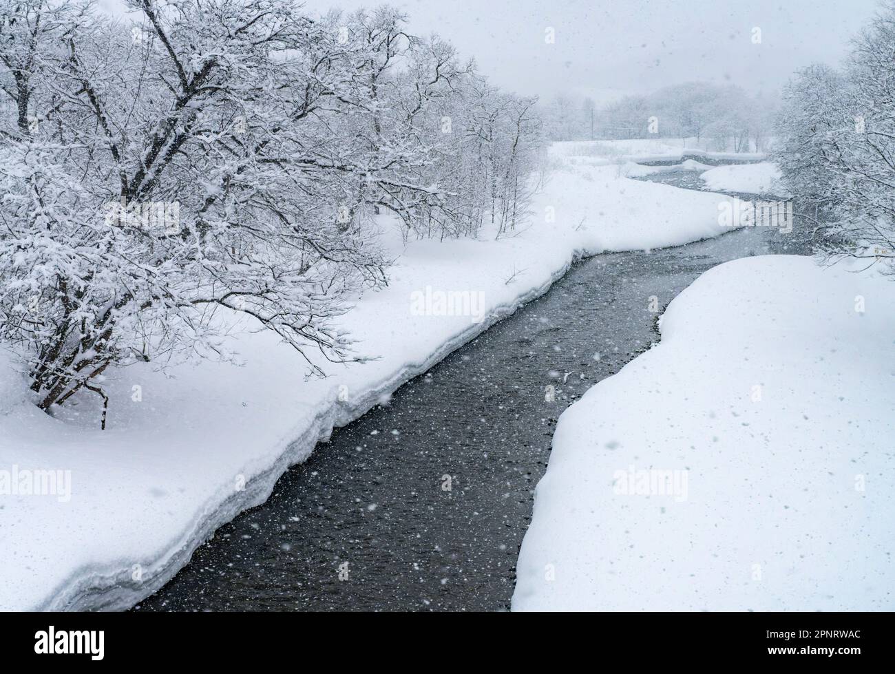 Der Fluss Futamata an einem verschneiten Tag, der von einem JR Hokkaido Zug auf der Hakodate Line aus gesehen wird. Stockfoto