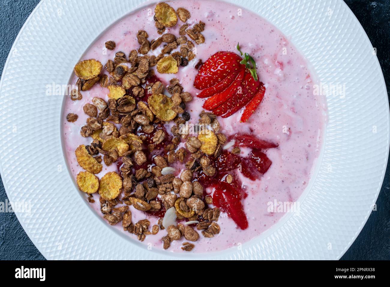 Weißer Teller mit roten Erdbeeren, Müsli und natürlichem Joghurt auf schwarzem Hintergrund, Nahaufnahme, Draufsicht Stockfoto