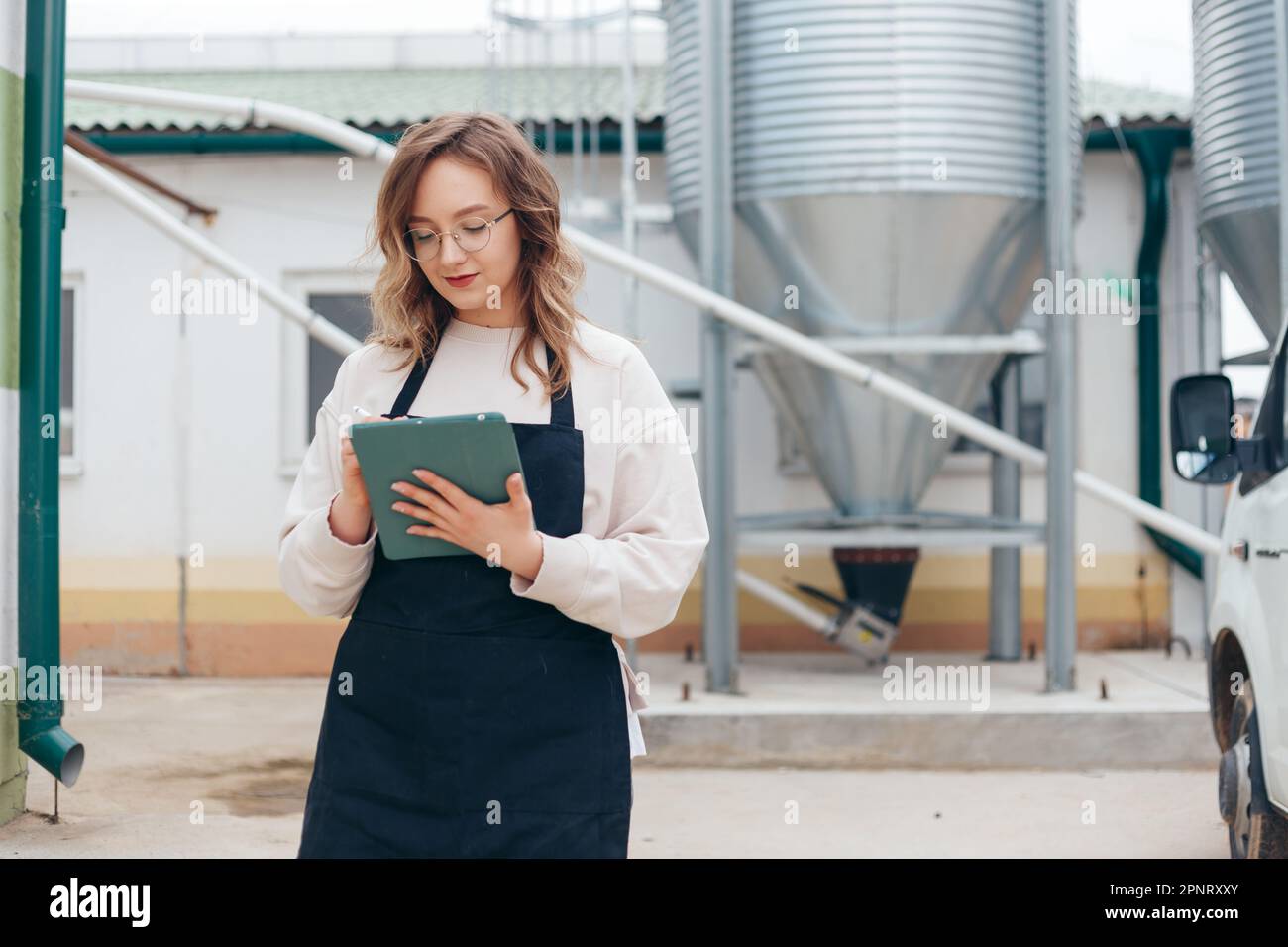 Frau Landwirtschaftsingenieurin mit Tablet in der Nähe von Cyclone Industrial Equipment Stockfoto