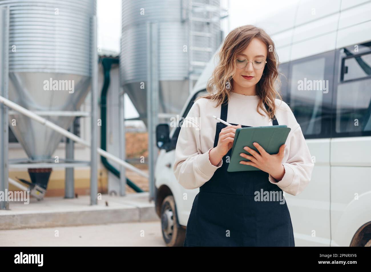 Eine Logistikerin mit Frachtbriefen steht in der Nähe eines Minibusses auf einer Produktionsfarm, Lieferung Stockfoto