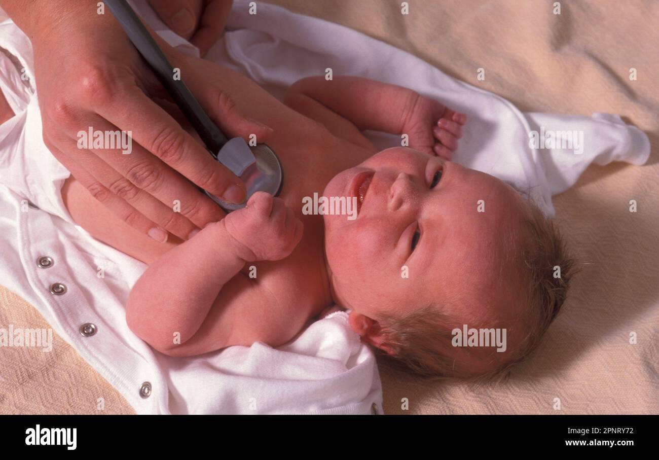 Routinemäßige postnatale Untersuchung, Hebamme hört den Herzschlag des Neugeborenen durch Stethoskop Stockfoto
