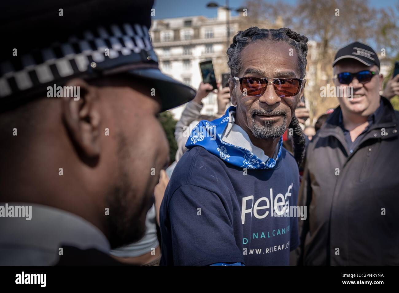 London, Großbritannien. 20. April 2023. Snoop Dogg Look-A-like trifft ein, um Polizeibeamte im Rahmen eines Werbeslogans für medizinisches Cannabis während der Pro-Cannabis-Feiern 420 im Hyde Park zu begrüßen. Hunderte nehmen an dem jährlichen Treffen im Jahr 4/20 in Hyde Park Teil, um einen Akt des massenhaften Ungehorsams zu begehen, indem sie Cannabis und seine Varianten rauchen, um gegen die aktuellen Gesetze zu protestieren, die Freizeitkonsumenten kriminalisieren. Im Vereinigten Königreich ist Marihuana eine Droge der Klasse B, und es ist illegal, zu Freizeitzwecken zu rauchen – das heißt, dass Personen, die im Besitz der Droge gefunden werden, mit einer Freiheitsstrafe von fünf Jahren oder einer Geldstrafe in unbegrenzter Höhe rechnen müssen. Kredit: Guy Corbishley/Alamy L. Stockfoto