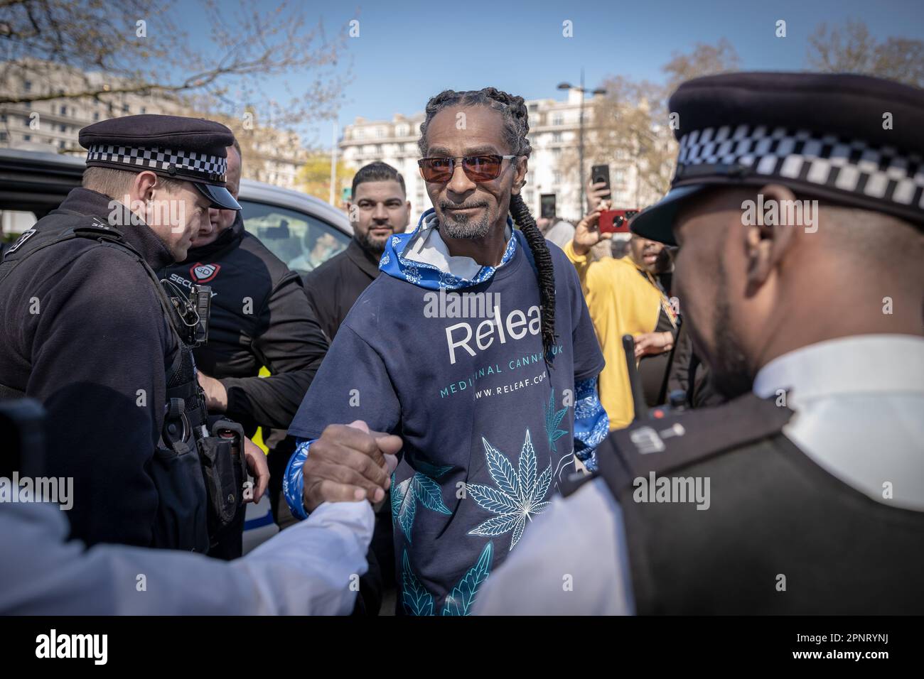 London, Großbritannien. 20. April 2023. Snoop Dogg Look-A-like trifft ein, um Polizeibeamte im Rahmen eines Werbeslogans für medizinisches Cannabis während der Pro-Cannabis-Feiern 420 im Hyde Park zu begrüßen. Hunderte nehmen an dem jährlichen Treffen im Jahr 4/20 in Hyde Park Teil, um einen Akt des massenhaften Ungehorsams zu begehen, indem sie Cannabis und seine Varianten rauchen, um gegen die aktuellen Gesetze zu protestieren, die Freizeitkonsumenten kriminalisieren. Im Vereinigten Königreich ist Marihuana eine Droge der Klasse B, und es ist illegal, zu Freizeitzwecken zu rauchen – das heißt, dass Personen, die im Besitz der Droge gefunden werden, mit einer Freiheitsstrafe von fünf Jahren oder einer Geldstrafe in unbegrenzter Höhe rechnen müssen. Kredit: Guy Corbishley/Alamy L. Stockfoto