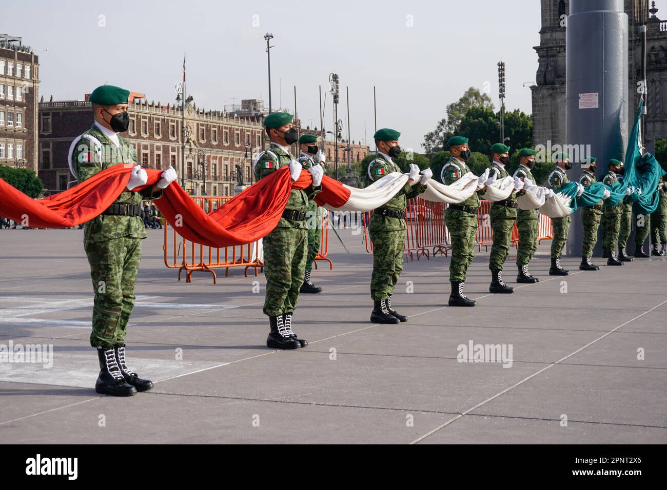Mitarbeiter des Verteidigungsministeriums hissen die Flagge am Constitution Plaza in Mexiko-Stadt. Die Zeremonie findet seit 1979 täglich statt, und mehr als 10 Personen müssen die Flagge tragen, die mehr als 200 kg (440 Pfund) wiegt. (Mar García/Global Press Journal) Stockfoto