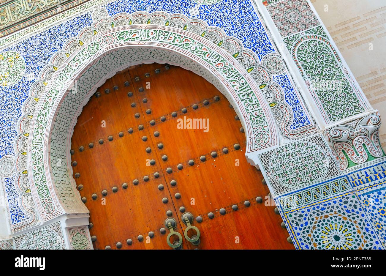 Fes, Marokko atemberaubende handbemalte Tür einer alten Moschee mit handgeschnitztem Putz. Stockfoto