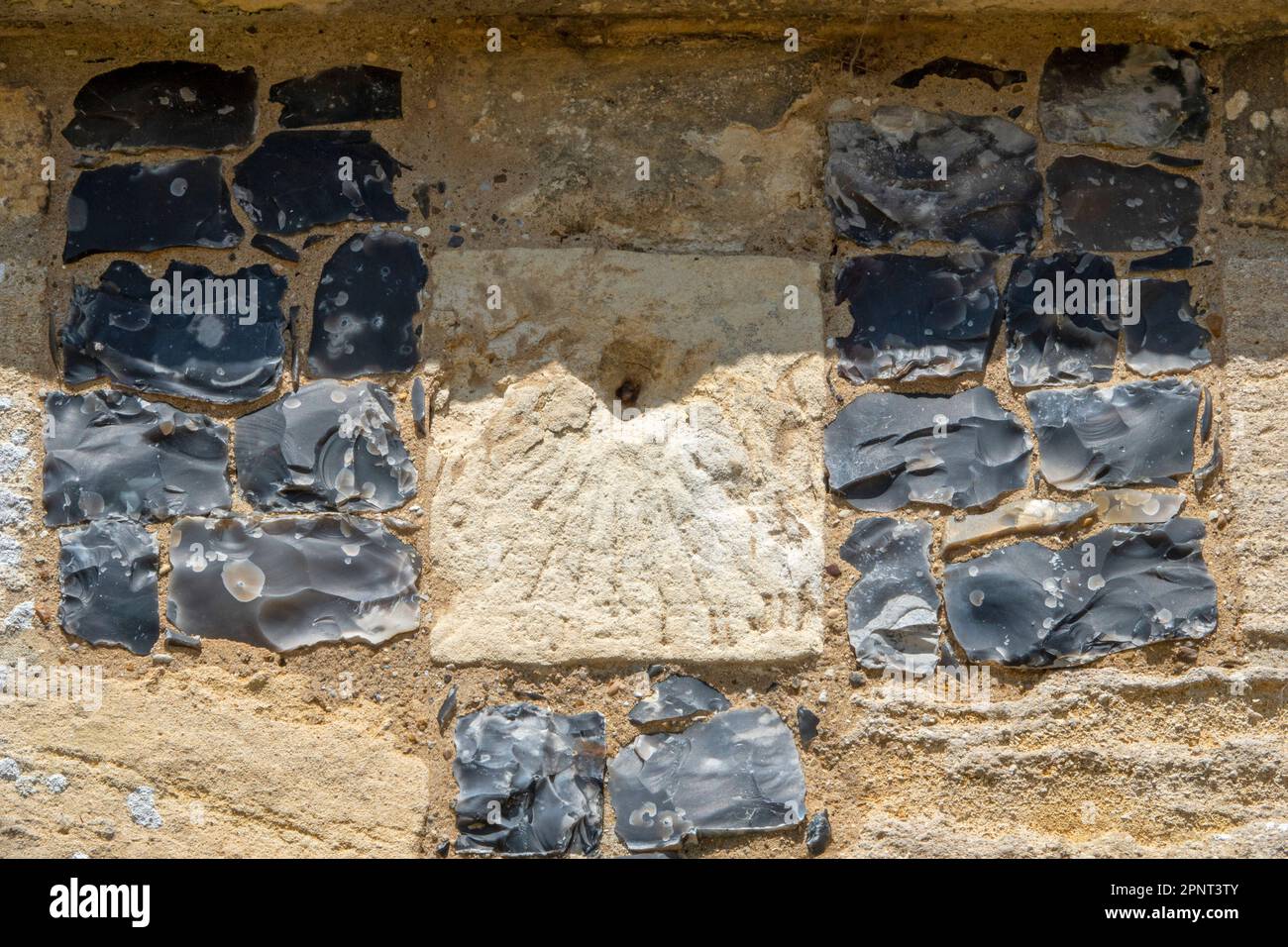 Die Überreste einer zerkratzten Sonnenuhr auf einem mit Feuerstein umrahmten Hintern in St. Mary, der Jungfrauenkirche, Parham, Suffolk Stockfoto