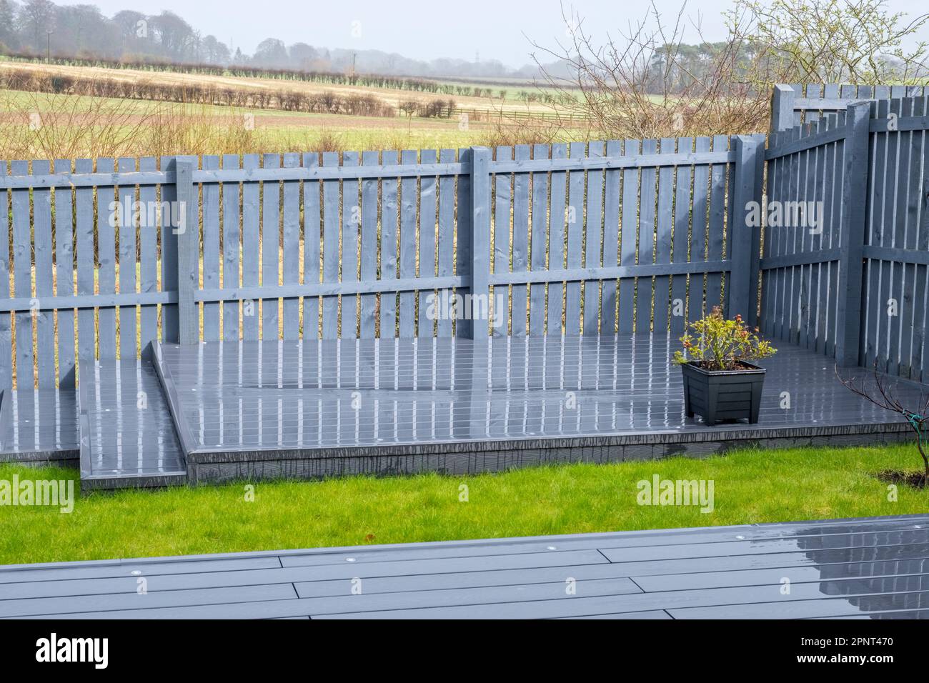 Aschegraue Terrassendielen aus Verbundwerkstoff auf zwei Ebenen an einem regnerischen, nassen Tag Stockfoto
