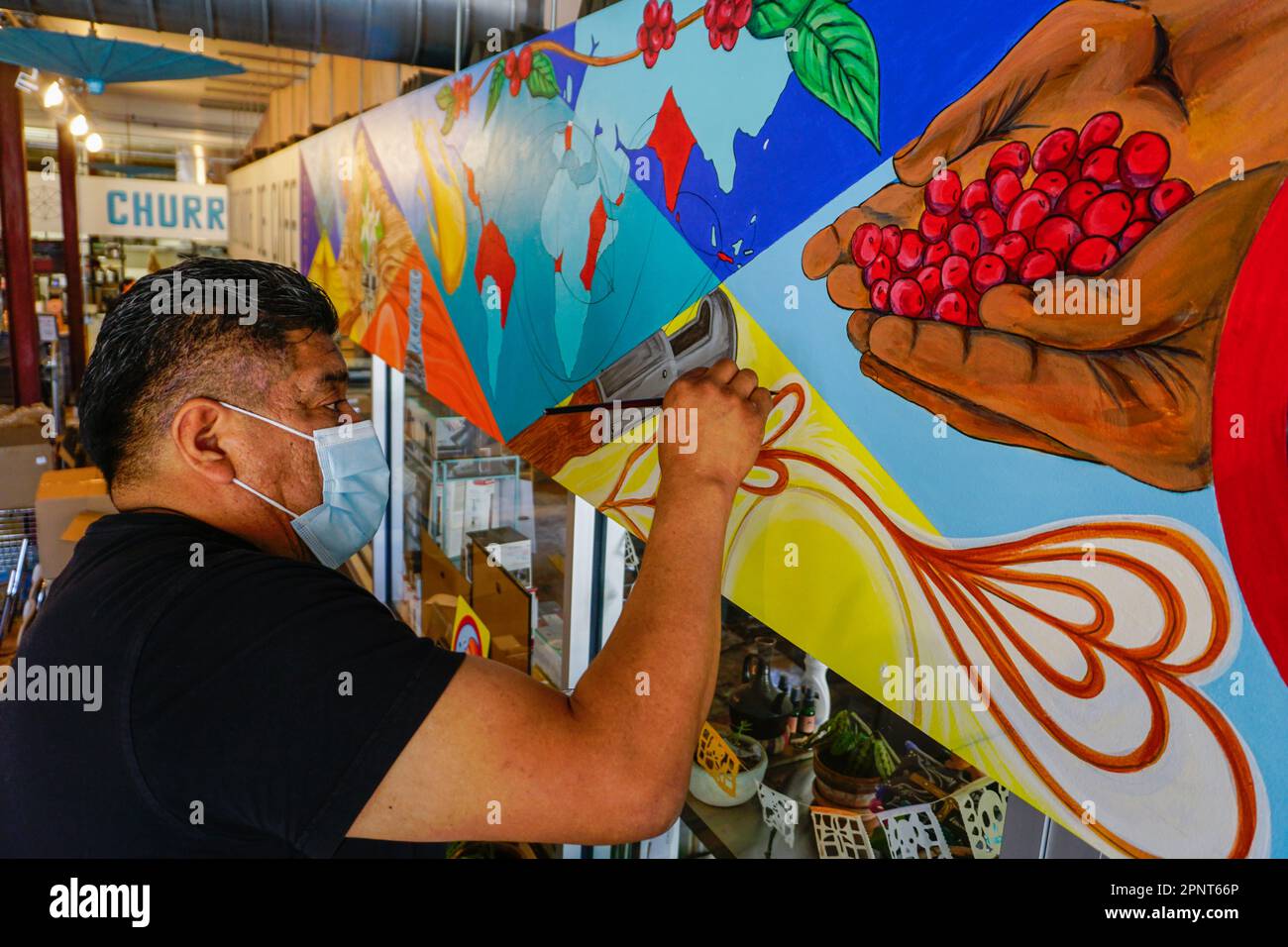 Cornelio Campos, der mit 18 aus Mexiko eingewandert ist, malt am 23. Oktober 2021 in Durham, North Carolina, USA, ein Wandgemälde in einem Café und churrería. Seine Bilder vermitteln, wie es ist, ein Migrant zu sein. Campos teilt gerne mit, wo er herkommt, und möchte jungen Menschen helfen, ihre Wurzeln zu erkennen. (Ena Aguilar Peláez/Global Press Journal) Stockfoto