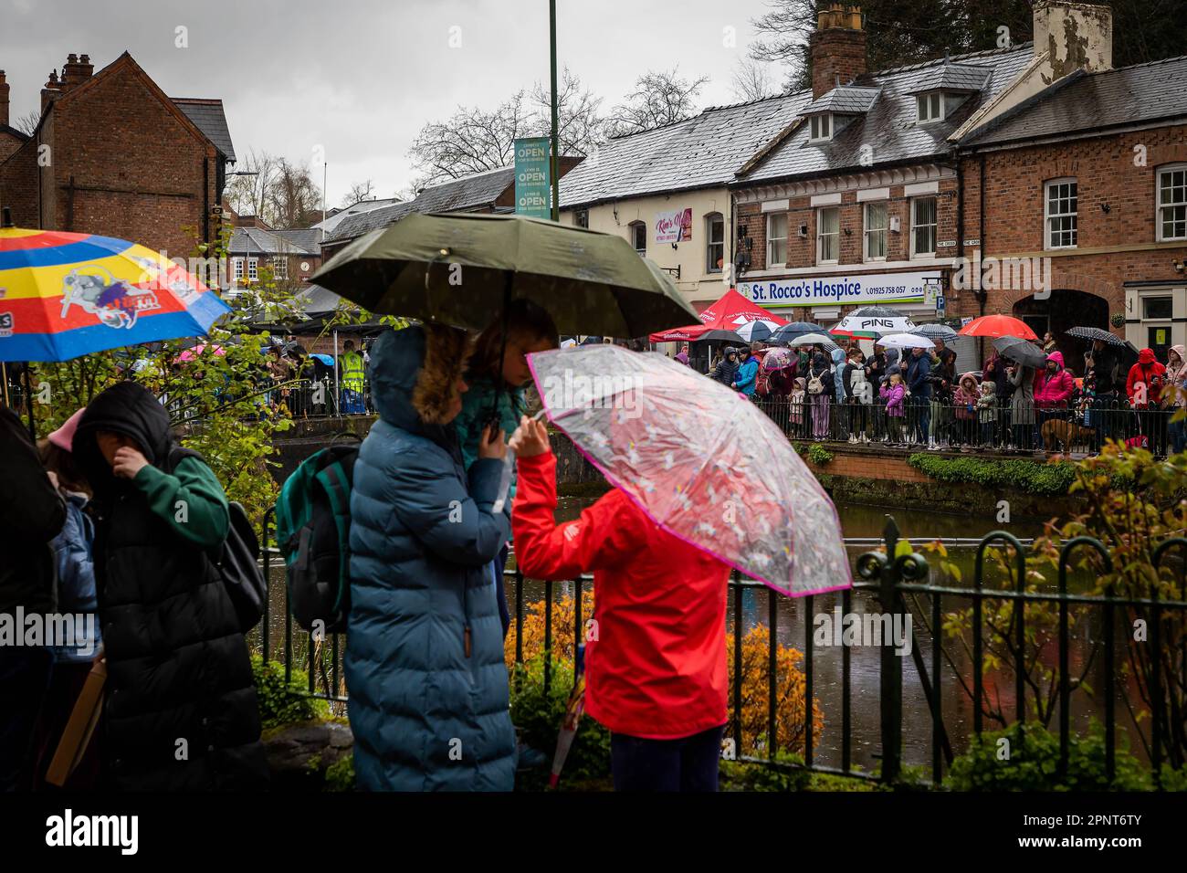 Menschen unter Regenschirmen warten im Dorf auf das Ende des alljährlichen Lymm-Entenrennens 2023. Stockfoto