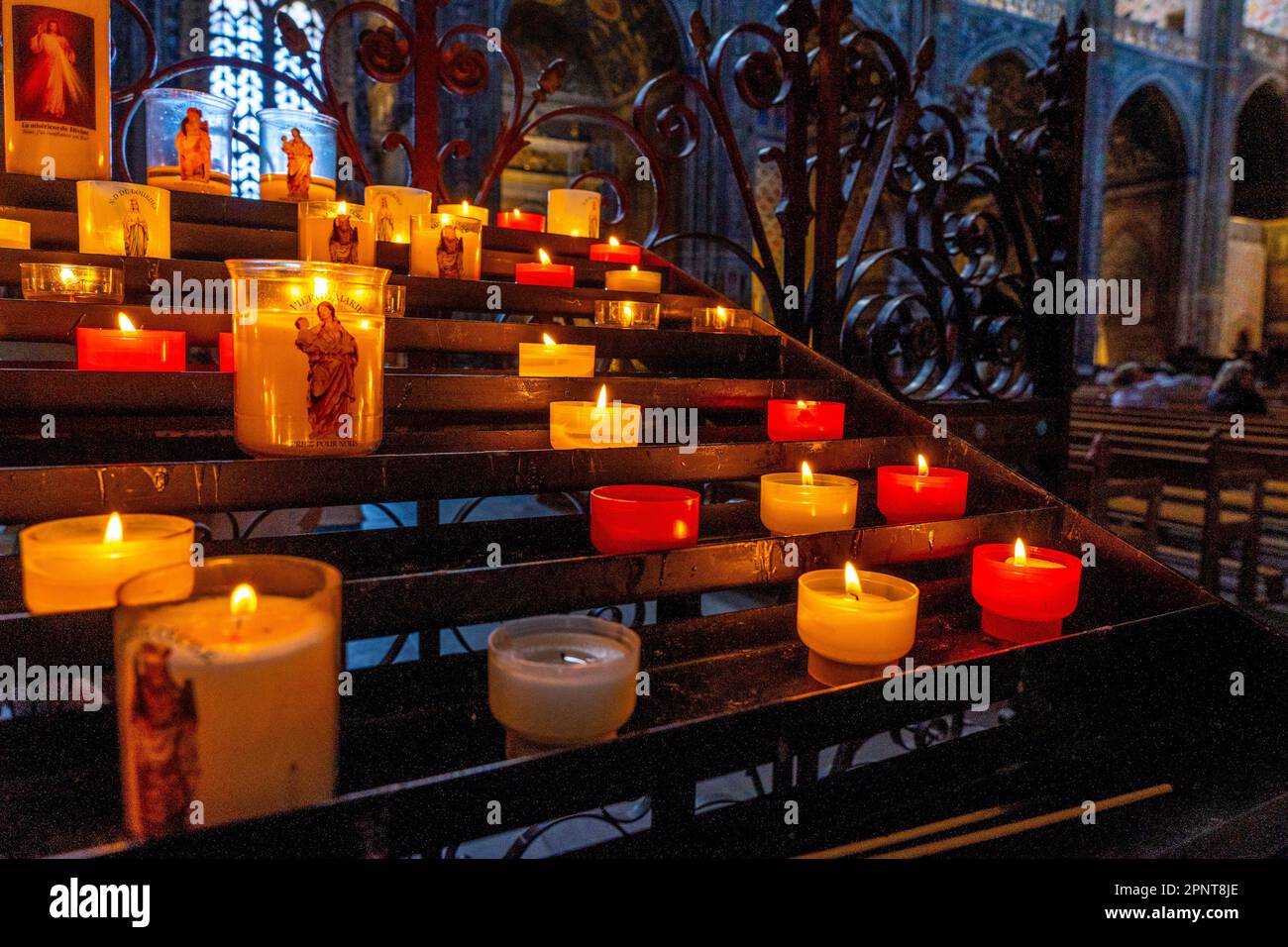 Kerzen in der katholischen Kirche. Wunderschöne Glasfenster mit dem Abendlicht im Hintergrund. Hochwertiges Foto Stockfoto