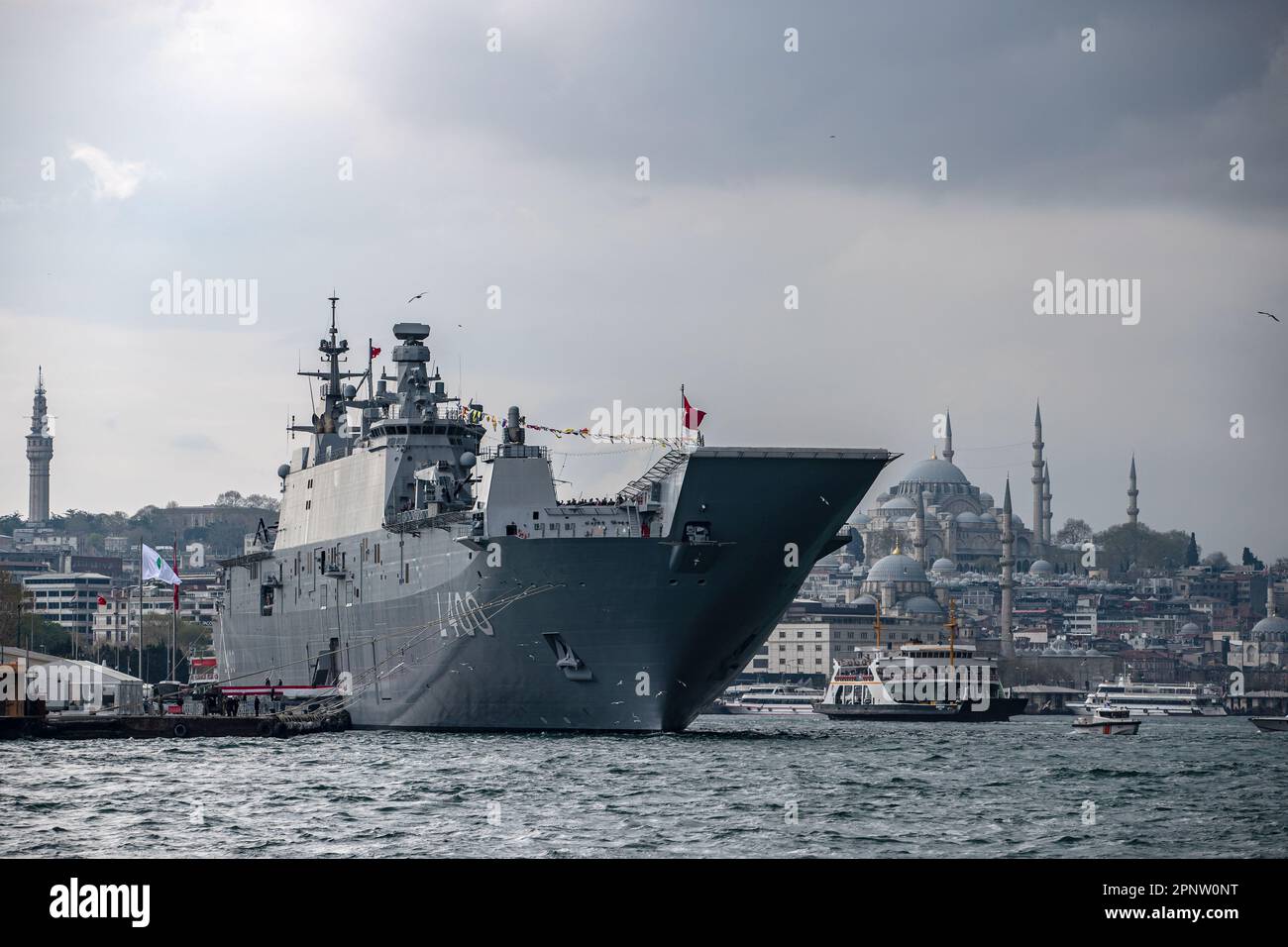 TCG Anadolu, im Hafen von Sarayburnu vor Anker, und die Suleymaniye-Moschee im Hintergrund. Das weltweit erste bewaffnete unbemannte Luftfahrtschiff (SIHA) und das größte Kriegsschiff der Türkei, das Mehrzweck-Amphibienschiff TCG Anadolu, wirft Anker im Hafen von Sarayburnu, während es für öffentliche Besuche im türkischen Istanbul öffnet. Das TCG Anadolu-Schiff ist bis April 23. für Besucher geöffnet. Stockfoto