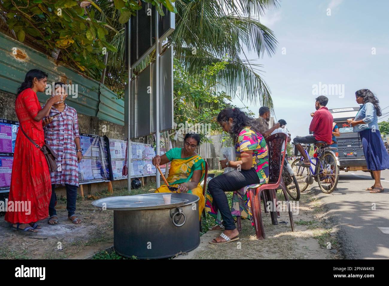 Vasugi Suthakar, Zentrum, gießt Reismehl in eine Tasse für Kulenthiran Pirintha, richtig, in Jaffna, Sri Lanka am 16. Mai 2022. Zur Erinnerung an die Mullivaikkal-Schlacht von 2009, eine der letzten im Bürgerkrieg in Sri Lanka, teilen sich die Menschen im Norden und Osten des Landes Reisbrei, das einzige Nahrungsmittel, das die Regierung den Bürgern zu dieser Zeit zur Verfügung stellte. (Vijayatharsiny Thinesh/Global Press Journal) Stockfoto