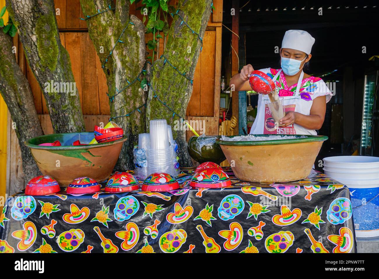 Perla Hernández gießt am 17. Dezember 2021 vor dem Familienrestaurant in San Andrés Huayapam, Oaxaca, Mexiko, Tejate, ein traditionelles alkoholfreies Getränk aus Mais und Kakao in eine Tasse. Tejate wird in der Regel in jícaras serviert, kleinen Behältern, die typischerweise aus der Frucht des Kalabaschbaums hergestellt werden, aber Hernández hat während der COVID-19-Pandemie Einwegbecher verwendet. (Ena Aguilar Peláez/Global Press Journal) Stockfoto