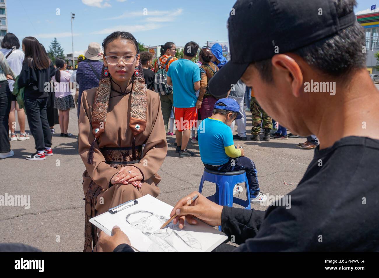 Nemekhnyam Buyantogtokh, rechts, zeichnet ein Porträt von Mandukhai Battsooj auf einer Modeveranstaltung in Erdenet, Provinz Orkhon, Mongolei am 12. Juni 2022. (Khorloo Khukhnohoi/Global Press Journal) Stockfoto
