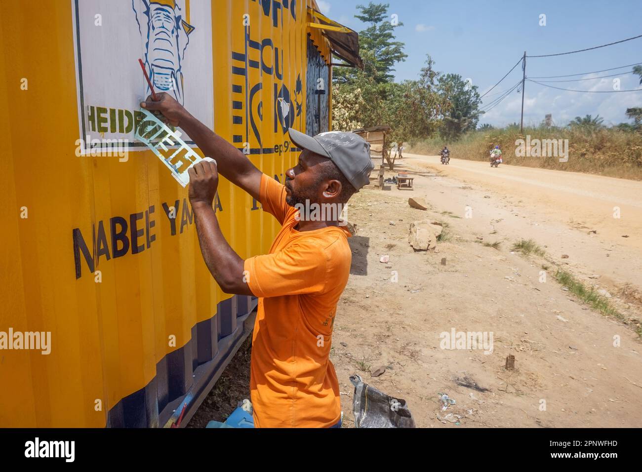 Jacques Moka zieht Briefe ab, die am 17. Mai 2022 in Kisangani, Demokratische Republik Kongo, verwendet wurden, um ein Wandgemälde für die Werbung für Zement zu erstellen. (Francoise Mbuyi Mutombo/Global Press Journal) Stockfoto