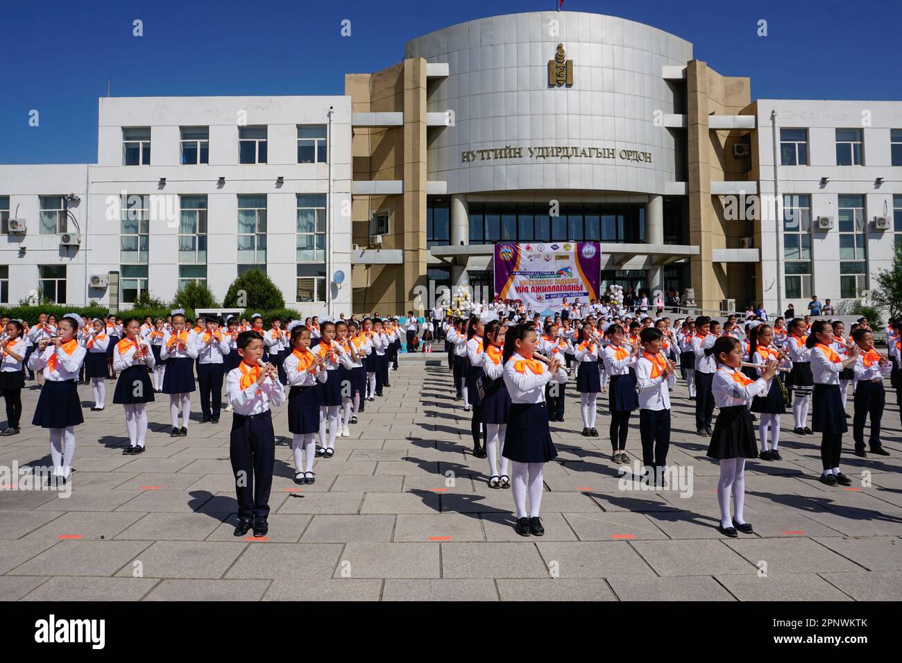 Schüler, die die Klassen 1 bis 12 von sieben Schulen vertreten, spielen am 21. Mai 2022 bei Abschluss einer außerschulischen Veranstaltung vor einem Regierungsgebäude in Dalanzadgad, Provinz Umnugovi, Mongolei, Rekorder. (Uranchimeg Tsoghuu/Global Press Journal) Stockfoto