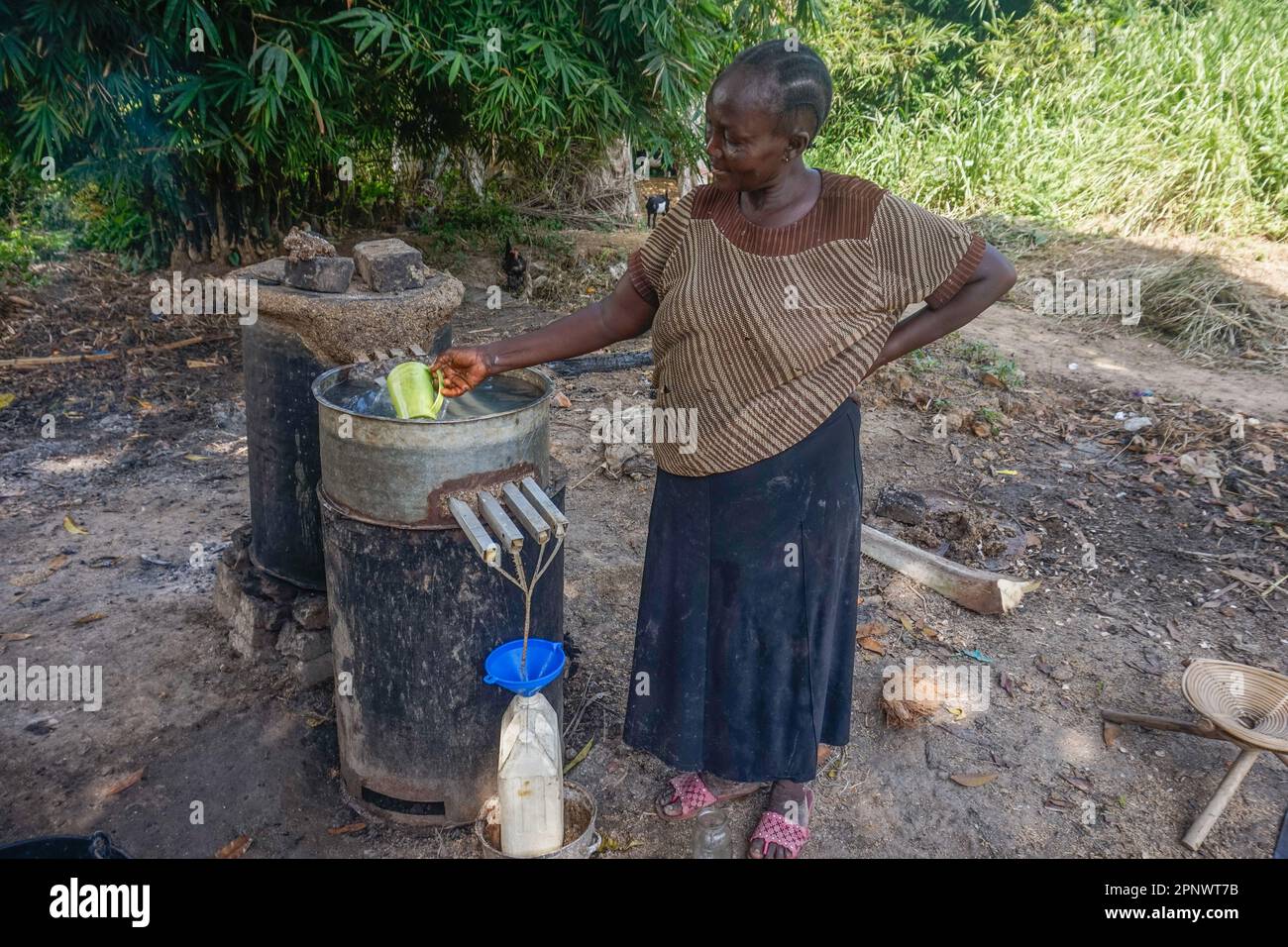 Brigitte Tosani stellt am 17. Mai 2022 in Kisangani, Demokratische Republik Kongo, handwerklich hergestellten Alkohol her, auch bekannt als Lotoko. Tosani, der seit mehr als 15 Jahren Lotoko herstellt, sagt, dass die fermentierten Maniok-Nebenprodukte in Destillationen aus Ölfässern destilliert werden. (Zita Amwanga/Global Press Journal) Stockfoto