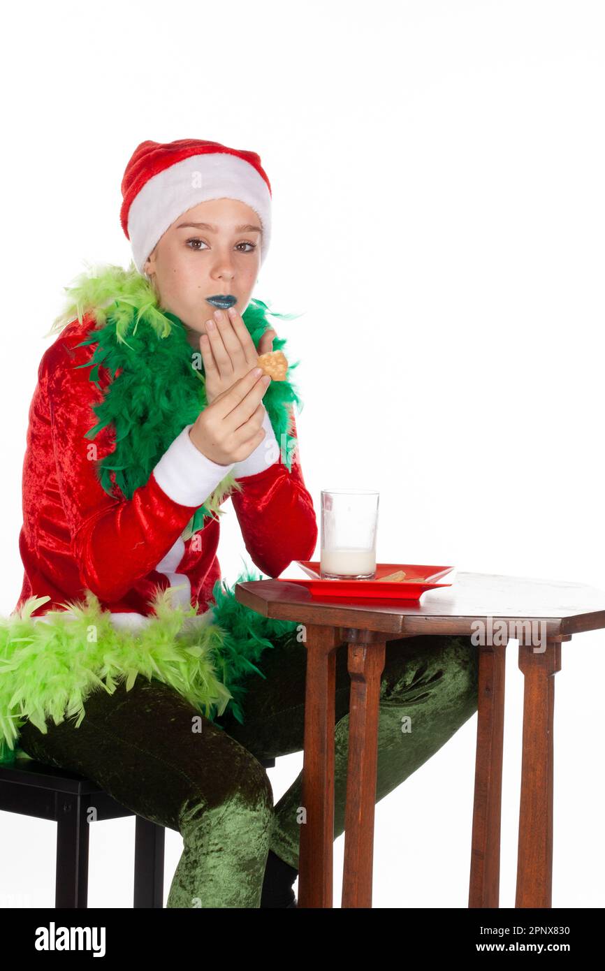Nahaufnahme eines jungen Mädchens mit rotem weihnachtsmann-Hut wie grinch-Mund, isoliert auf weißem Hintergrund. Freche menschliche Emotio Stockfoto