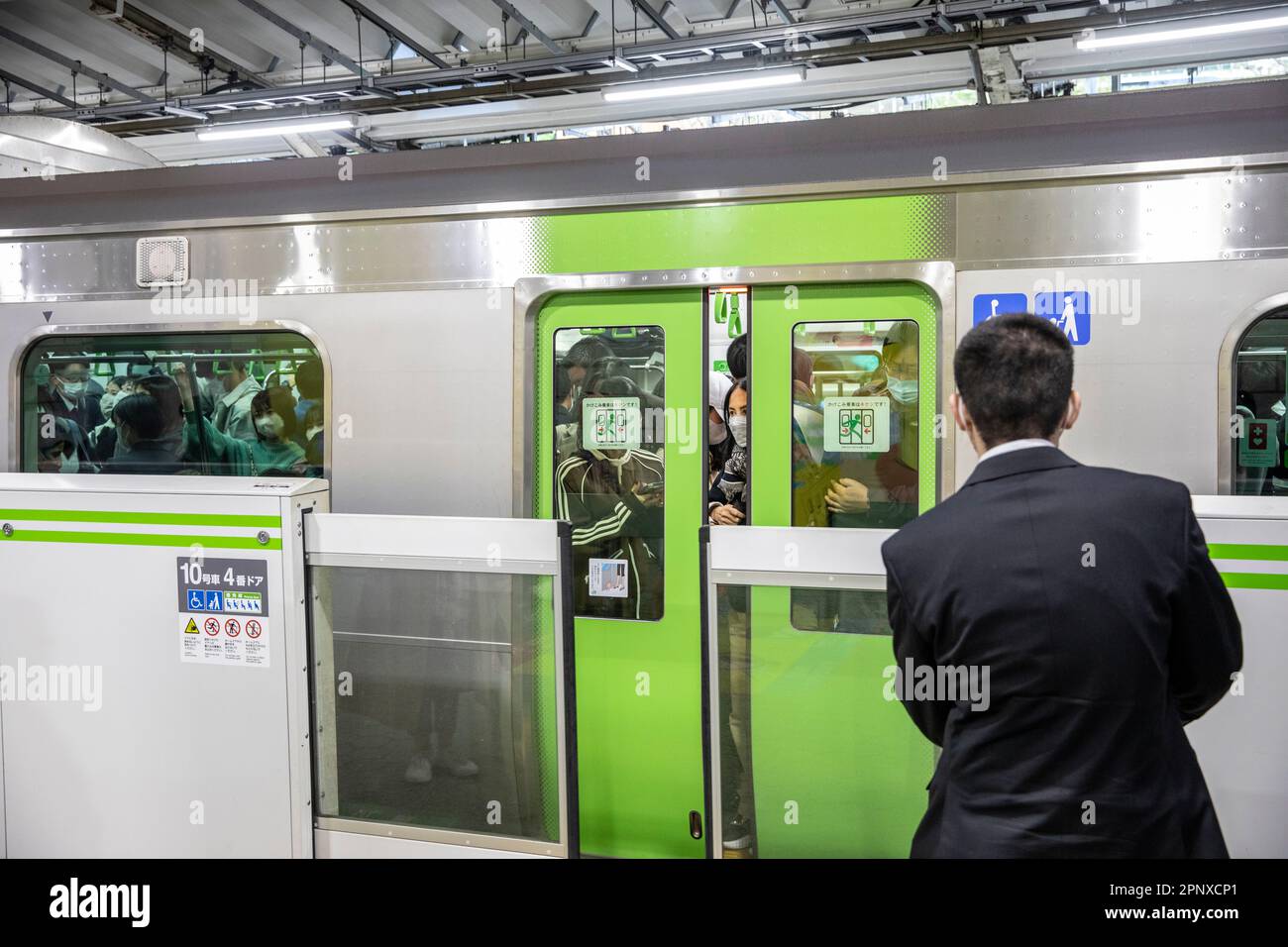Überfüllter Zug in Tokio, April 2023, überfüllte Zugtüren schließen, während ein japanischer Mann auf die nächste U-Bahn, Japan, Asien, wartet Stockfoto